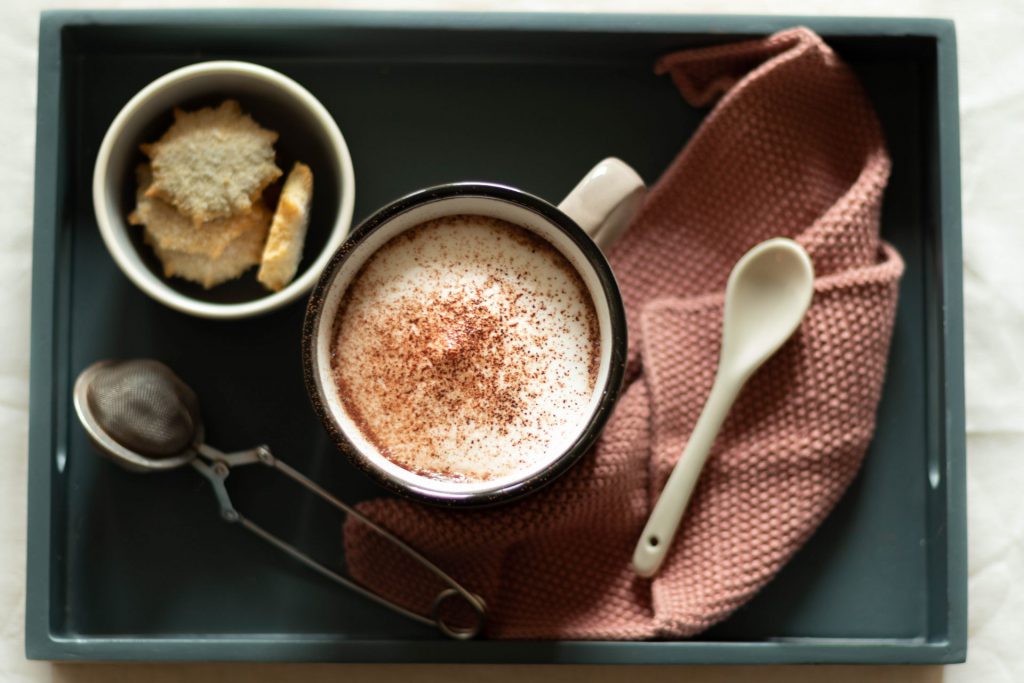 Tasse heiße Schokolade mit Milchschaum auf einem Tablett von oben fotografiert