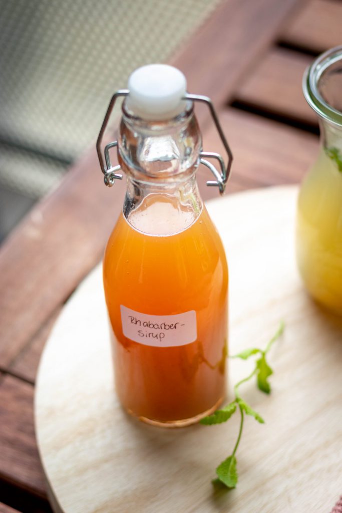 Eine Flasche Rhabarbersirup auf einem Holztablett